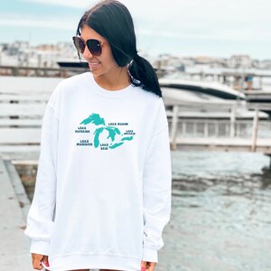 May include: White sweatshirt with a teal outline of the Great Lakes and the names of each lake: Lake Superior, Lake Huron, Lake Michigan, Lake Erie, and Lake Ontario.