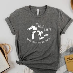 May include: A gray t-shirt with a white graphic of the Great Lakes and the text "The Great Lakes Always Fresh & Sometimes Frozen".