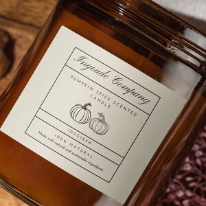 Può includere: Un barattolo di vetro marrone con una candela e un'etichetta bianca che recita "Ingoude Company Pumpkin Spice Scented Candle 100g/24h 100% Natural Made with natural and sustainable ingredients".