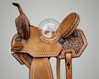 Könnte beinhalten: Ein brauner Ledersattel mit weißen Nähten und floralen Verzierungen. Der Sattel hat ein "Unicon Saddlery Horse Paradise" Logo auf dem Hinterzwiesel.
