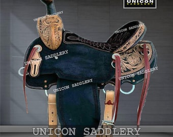 Puede incluir: Una silla de montar western de cuero negro y marrón con intrincados grabados florales. La silla presenta un asiento oscuro, detalles en cuero claro y el texto "UNICON SADDLERY".