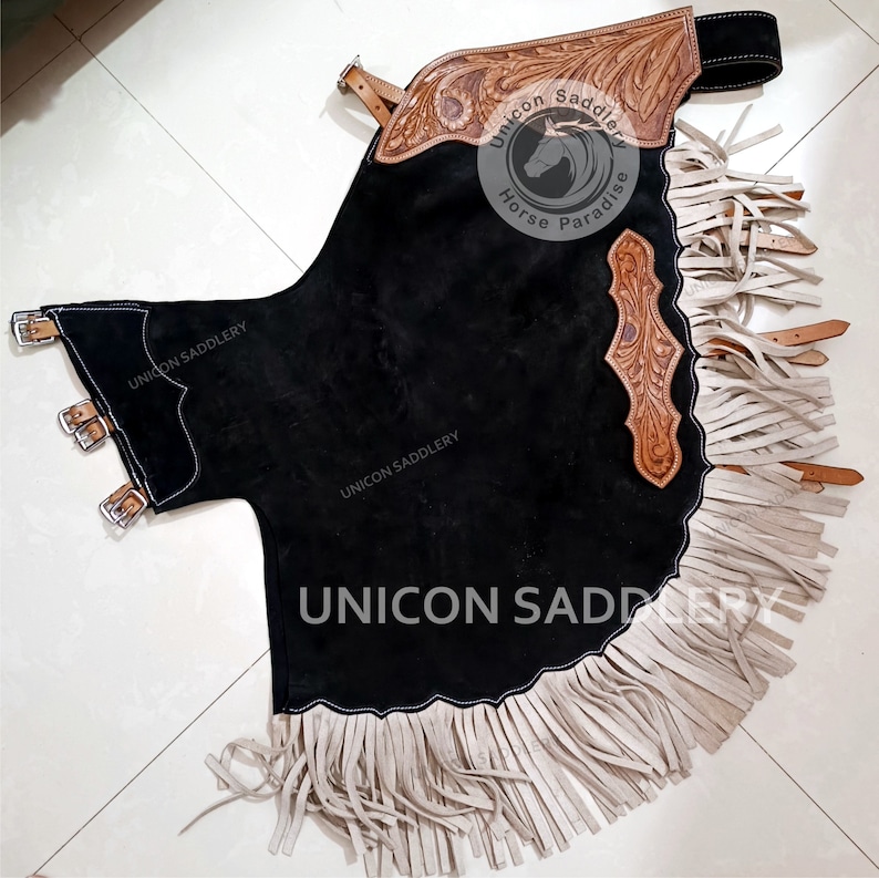May include: Black leather chaps with white fringe and brown leather accents. The chaps have a decorative design with a horse and the text "Unicon Saddlery Horse Paradise".