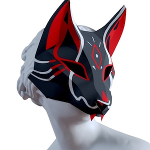 Peut inclure: Un masque de renard noir et rouge avec des accents blancs. Le masque a un design g&eacute;om&eacute;trique et un museau pointu.