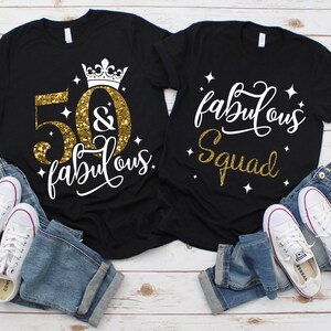Pode incluir: Duas camisetas pretas com glitter dourado e texto branco. Uma camiseta diz "50 & fabulous" com uma coroa acima do 50. A outra camiseta diz "fabulous squad".