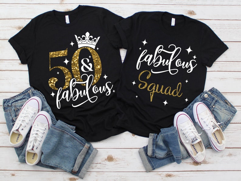 Pode incluir: Duas camisetas pretas com glitter dourado e texto branco. Uma camiseta diz "50 & fabulous" com uma coroa acima do 50. A outra camiseta diz "fabulous squad".