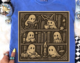 May include: A blue Comfort Colors t-shirt with a brown graphic of ghosts in Halloween scenes. The graphic includes ghosts reading, drinking coffee, and with pumpkins. The shirt has a crew neck and short sleeves.