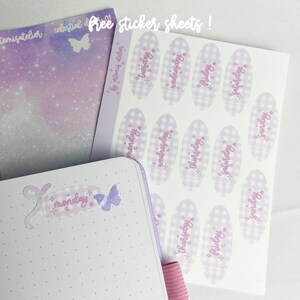 May include: A sheet of stickers with a gingham pattern and days of the week written in a purple script. The stickers are on a white background. The sheet is labeled "Free sticker sheets!" in a purple script.