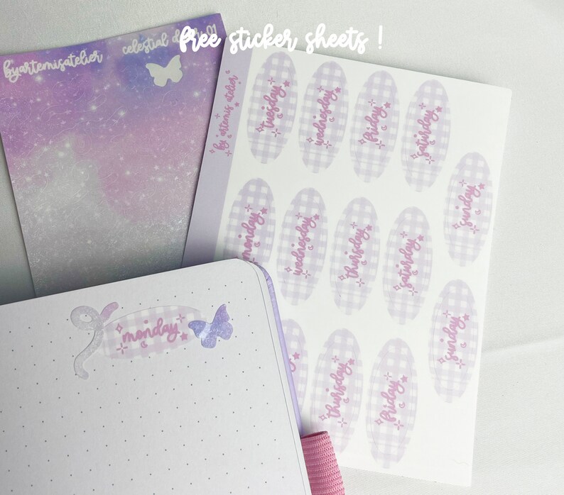 May include: A sheet of stickers with a gingham pattern and days of the week written in a purple script. The stickers are on a white background. The sheet is labeled "Free sticker sheets!" in a purple script.