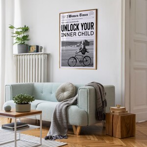 May include: A black and white photo of a woman riding a bicycle. The photo is framed and hanging on a white wall. The photo is titled "Unlock Your Inner Child" and is from the "Women Times" newspaper.