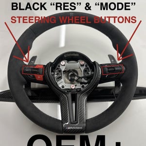 Op de afbeelding: Een zwart BMW F Series stuurwiel met zwarte "RES" en "MODE" knoppen. Het stuur heeft een middenstuk van koolstofvezel en is gemarkeerd met "OEM+". De stuurknoppen zijn rood en zwart.