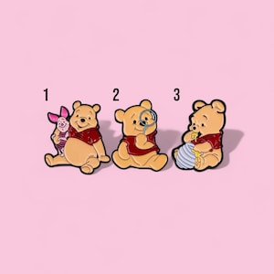 May include: Three cartoon character pins featuring Winnie the Pooh. One pin shows Pooh with Piglet, another with a magnifying glass, and the last with a honey pot. Each character wears a red shirt and has a black outline.