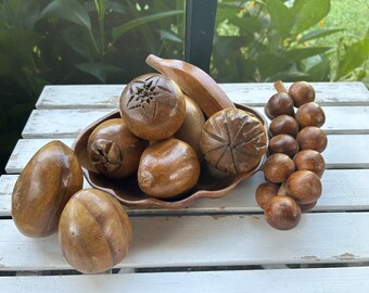 May include: A wooden bowl filled with carved wooden fruit, including a banana, a starfruit, and a pineapple. A string of wooden beads is also included.