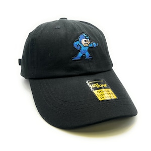 May include: Black baseball cap with an embroidered blue pixelated character, a video game character, on the front. The cap has a yellow tag that says "Official Licensed Product" and "HAZONE".