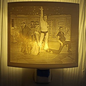 May include: A white night light with a 3D printed image of four people in a room. The image is in shades of grey and white.