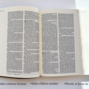 May include: Open Bible with double-column format, satin ribbon marker, and text in red. The book has a brown leather cover and is open to a page with printed text. The text includes the words of Jesus in red.