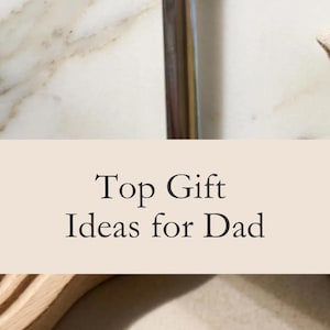 May include: A polished stainless steel spoon shaped like a miniature shovel with the text DAD'S ICE CREAM SHOVEL engraved on the bowl. The spoon features a pointed tip and a smooth, rounded handle, reflecting light on its metallic surface.