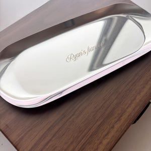 Op de afbeelding: Een langwerpig, ovaalvormig dienblad van zilverkleurig metaal met een gepolijst, reflecterend oppervlak. Het dienblad is voorzien van de gegraveerde tekst "Ryan's fiance" in een cursief lettertype op de platte bodem.