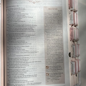 K&ouml;nnte beinhalten: Offene Bibel mit dem Titel "Psalmen" und Text. Die Seite zeigt Text und einen Abschnitt mit dem Titel "Meditation". Die Buchseiten haben farbige Register.