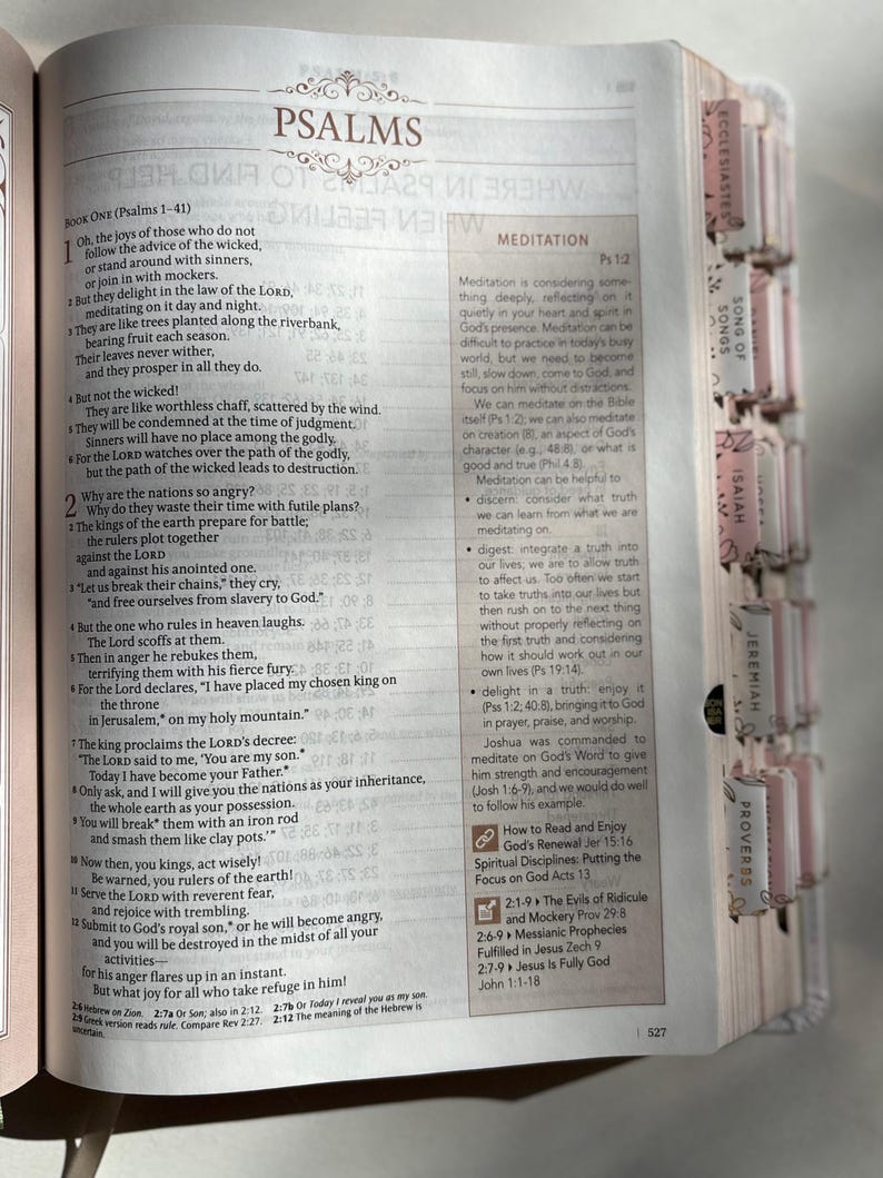 K&ouml;nnte beinhalten: Offene Bibel mit dem Titel "Psalmen" und Text. Die Seite zeigt Text und einen Abschnitt mit dem Titel "Meditation". Die Buchseiten haben farbige Register.