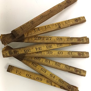 May include: A set of eight wooden folding rulers with black markings. The rulers are numbered from 1 to 71. The rulers are made in the USA.
