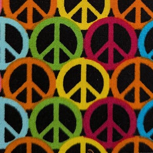 May include: A black fabric with a repeating pattern of colorful peace signs. The peace signs are in various colors, including pink, orange, yellow, green, blue, and red.