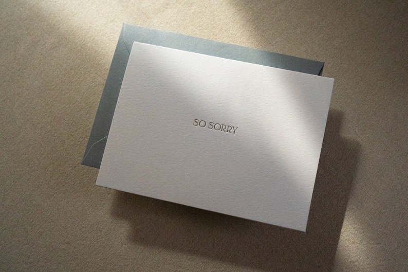 Sympathy card letterpress printed with So Sorry in matte gold ink onto bright white cotton paper with a blue envelope