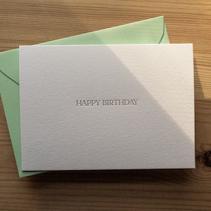 Happy birthday card letterpress printed in matte gold ink onto bright white cotton paper with a light green envelope