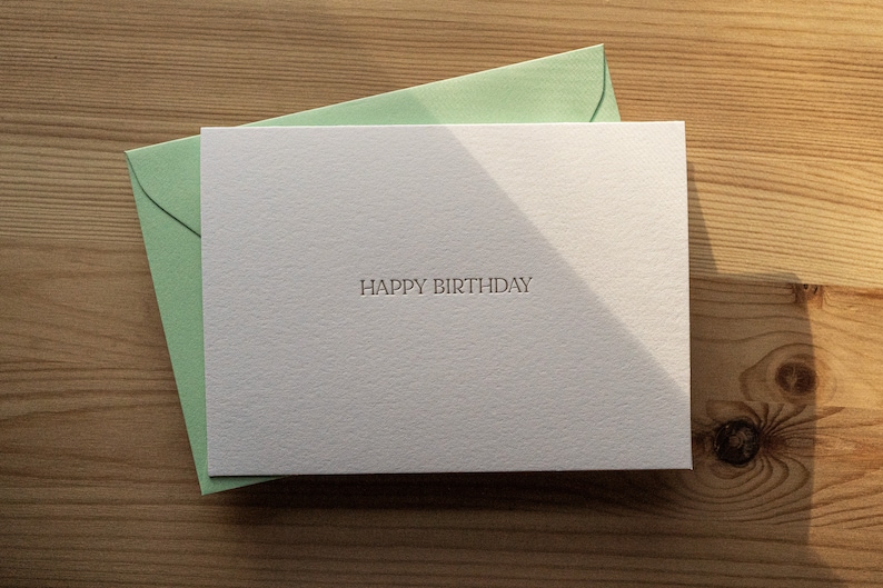 Happy birthday card letterpress printed in matte gold ink onto bright white cotton paper with a light green envelope