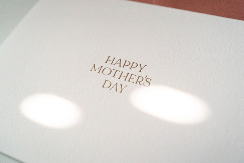 Peut inclure: Une carte blanche avec le texte "Happy Mother's Day" imprim&eacute; en lettres dor&eacute;es.