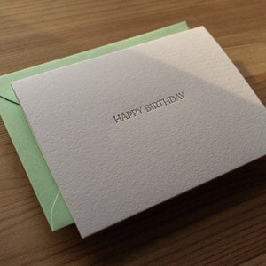 Happy birthday card letterpress printed in matte gold ink onto bright white cotton paper with a light green envelope