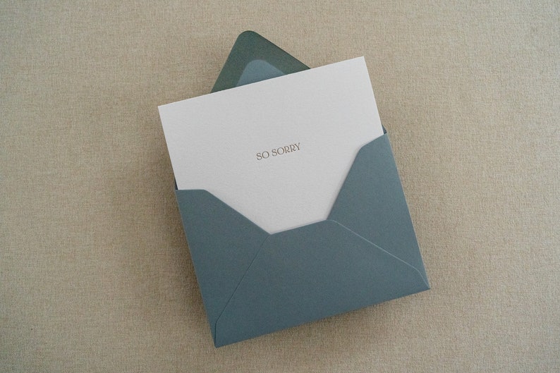 Sympathy card letterpress printed in matte gold ink onto bright white cotton paper with a blue envelope