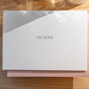 Anniversary card letterpress printed in matte gold ink onto bright white cotton paper with a light pink envelope