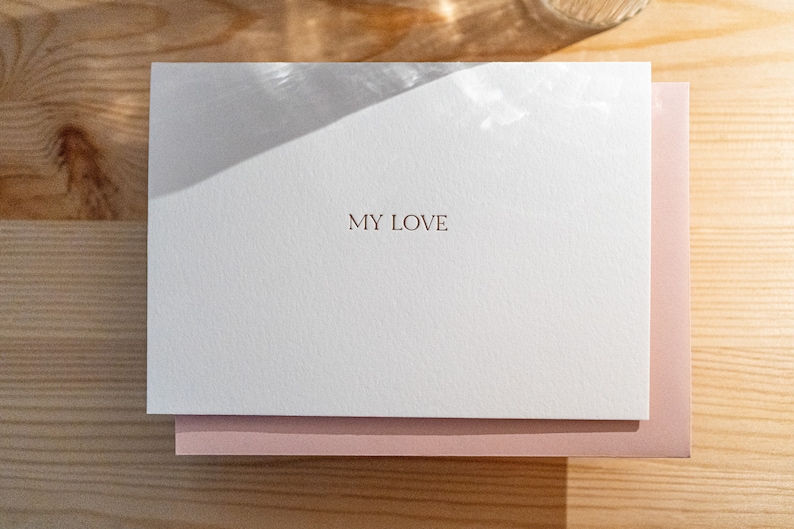 Anniversary card letterpress printed in matte gold ink onto bright white cotton paper with a light pink envelope