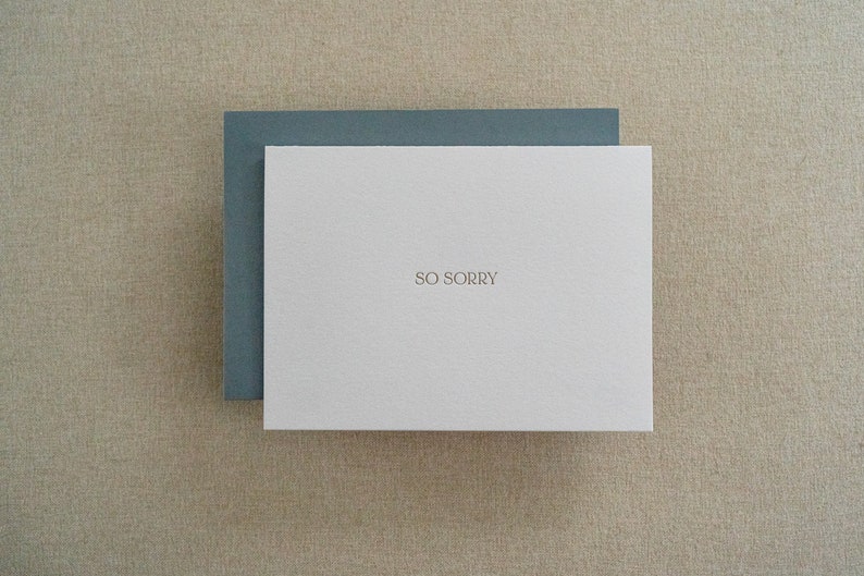 Sympathy card letterpress printed in matte gold ink onto bright white cotton paper with a blue envelope