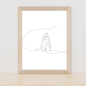 Op de afbeelding: Een zwart-witte lijntekening van een persoon die op een golf surft. De tekening is ingelijst in een licht houten lijst en hangt aan een witte muur.