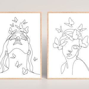 May include: Two black and white line art prints of a woman's face with butterflies around her head. The woman in the left print has butterflies around her head and neck. The woman in the right print has butterflies around her head and shoulders.