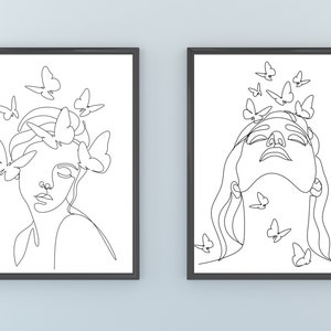 May include: Two black framed prints with white line drawings of a woman's face with butterflies around her. The woman in the left print has butterflies around her head and the woman in the right print has butterflies around her neck.