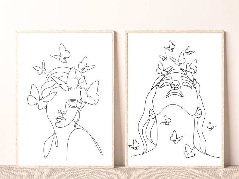 May include: Two black and white line art prints of a woman's face with butterflies around her head. The woman in the left print has her eyes closed, while the woman in the right print has her eyes open and is looking up.
