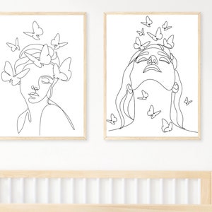 May include: Two black and white line drawings of women's faces with butterflies surrounding them. The drawings are framed in simple wooden frames.