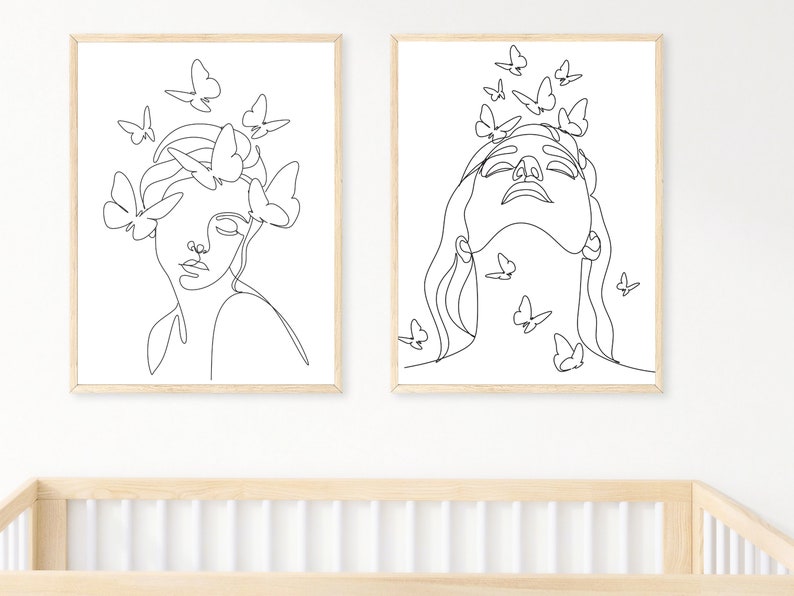 May include: Two black and white line drawings of women's faces with butterflies surrounding them. The drawings are framed in simple wooden frames.