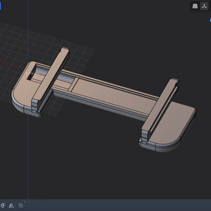 Könnte beinhalten: Ein 3D-Modell einer grauen Kunststoffklemme mit rechteckiger Form und abgerundeten Kanten. Die Klemme ist so konzipiert, dass sie zwei Materialstücke zusammenhält.