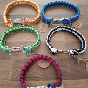 May include: Four colourful braided dog collars with silver clasps. Each collar has a small brown tag that says "Handmade with love".