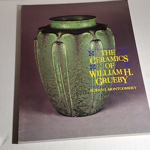 May include: A book cover featuring a green ceramic vase with a textured surface. The title of the book is "The Ceramics of William H. Grueby" by Susan J. Montgomery.