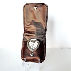 May include: A brown heart-shaped watch case with a silver heart-shaped watch with rhinestones inside. The watch case is open and the watch is visible.