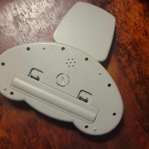 May include: A light gray electronic device with a rectangular lid and a rounded base. The base has a battery compartment, several small holes, and the text "PRO-Fresh". The device is on a wooden surface.