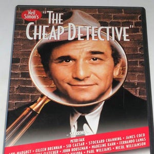 May include: DVD case for "The Cheap Detective" movie. The cover features a man's face magnified by a gold-handled magnifying glass. The title is in white, with the actor's name and supporting cast listed below.