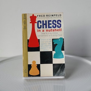 May include: A vintage book titled "CHESS in a nutshell" by Fred Reinfeld. The cover features a red king chess piece, a blue knight, and an orange pawn against a black and white checkered background. The book is a guide on how to play chess.