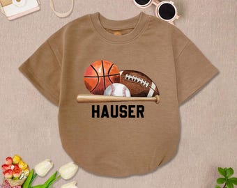 May include: A brown t-shirt with a baseball, basketball, football, and baseball bat graphic. The text "HAUSER" is printed below the graphic.