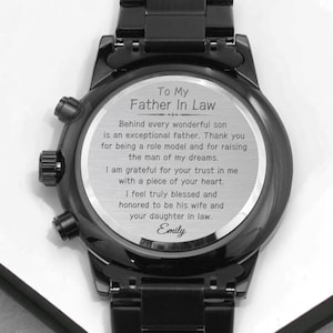 May include: Black wristwatch with a silver face and engraved message. The message reads "To My Father In Law Behind every wonderful son is an exceptional father. Thank you for being a role model and for raising the man of my dreams. I am grateful for your trust in me with a piece of your heart. I feel truly blessed and honored to be his wife and your daughter in law. Emily"