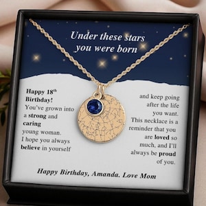 May include: Gold-colored necklace with a round pendant featuring a blue gemstone and a celestial map design. The necklace is presented in a black box with text that reads "Under these stars you were born" and a birthday message.